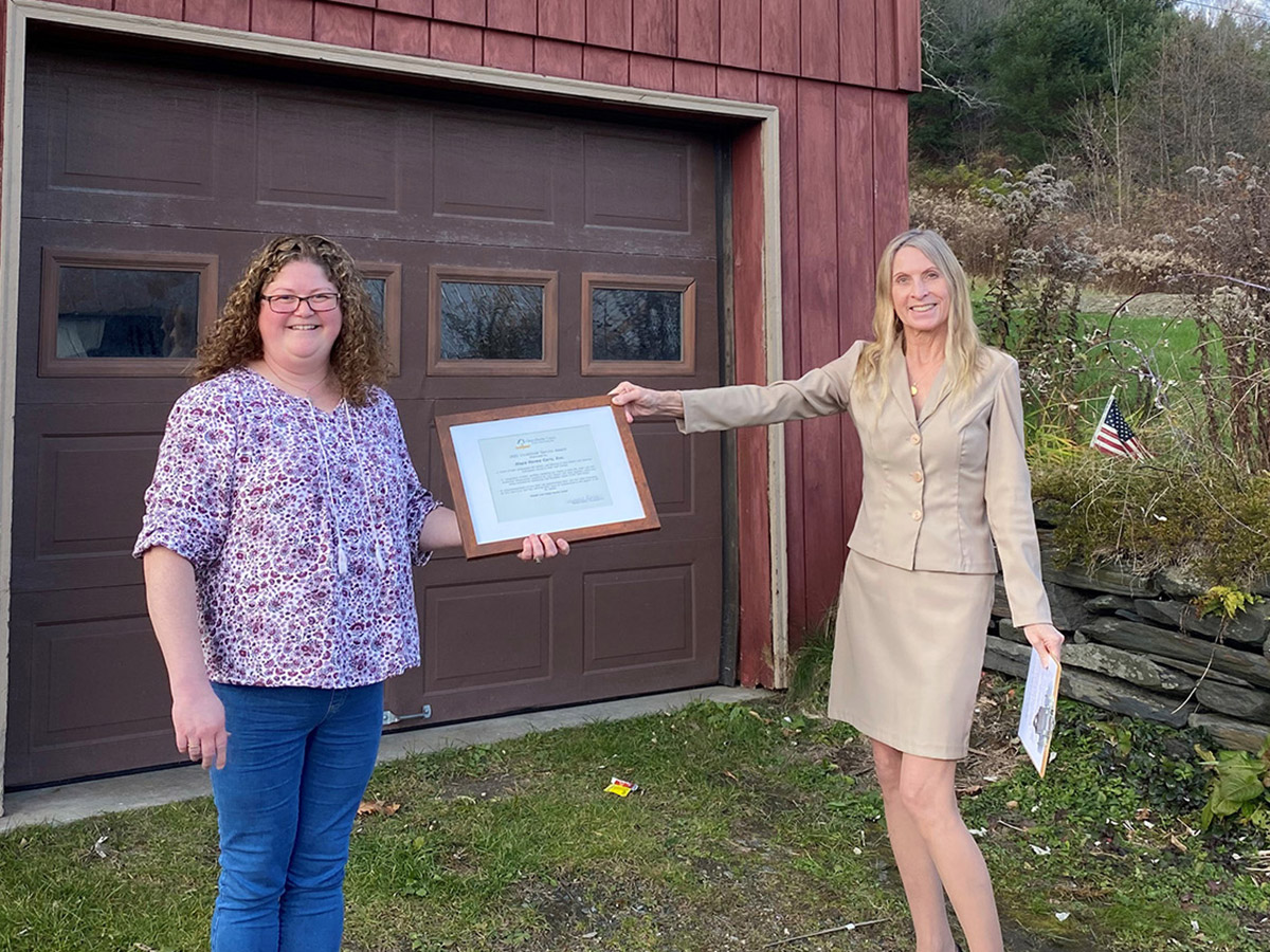 Female Hope Home Care employee accepting the 2021 Vocational Service Award from a female Clara Martin Center employee
